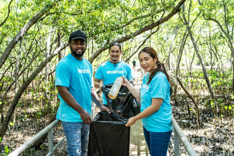 3 personas con camisitas azules, que pone volunteer de fondo bosque