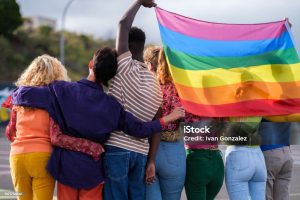 Grupo de personas jovenes sujetando una bandera arcoiris o lgbti+