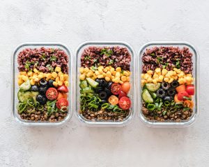 Tres recipientes de vidrio con comida saludable preparada y organizada, listos para la semana.
